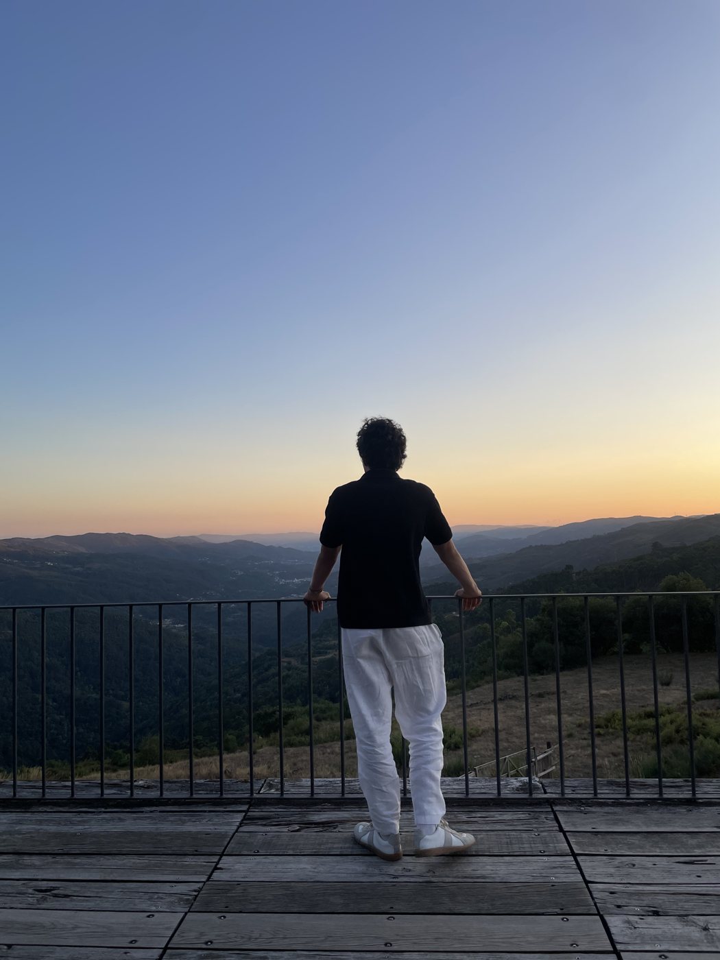 Lucas Salvador on a terrace, looking at the mountains at sunset